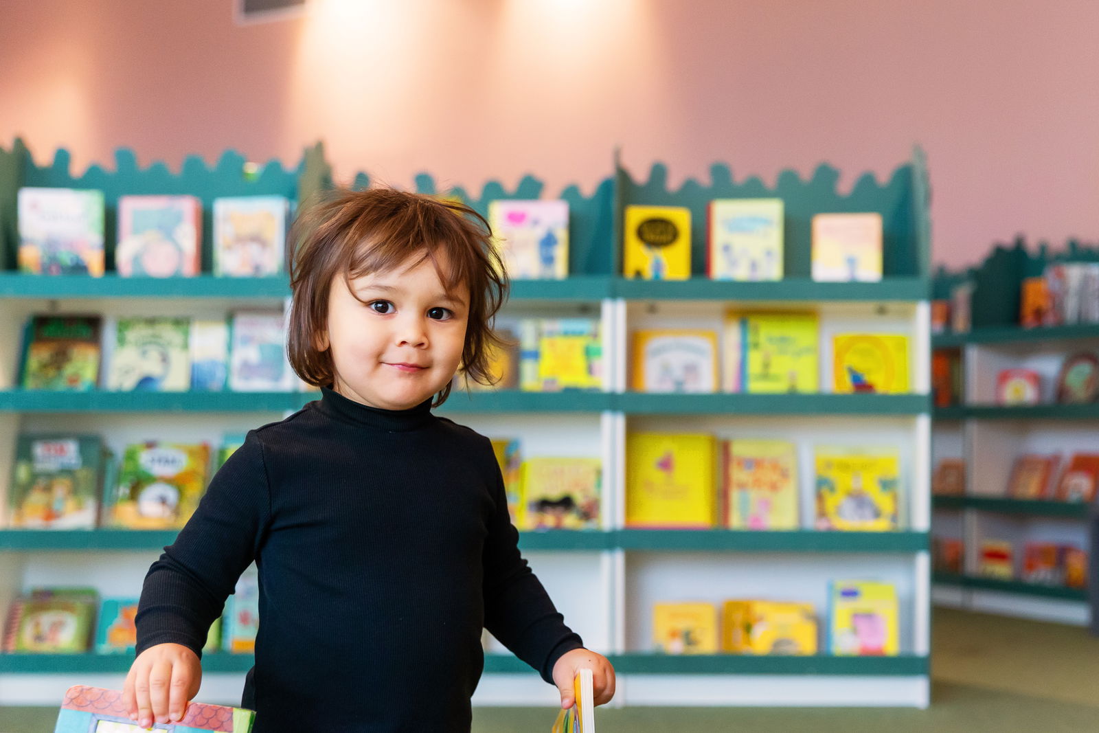 Foto: Matilda Rahm Ett barn framför bokhyllor i bibliotek Rum för Barn.