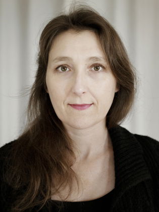 Författaren Marie Darrieussecq, med långt brunt hår och svart tröja, tittar rakt mot kameran.