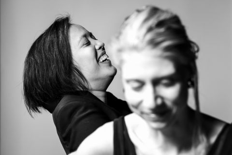 Foto: Sara P Borgström Svartvit bild på två kvinnor, en med axellångt mörkt hår som skrattar, den andra med blont hår suddig i förgrunden.