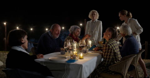 En grupp människor sitter vid ett dukat långbord.