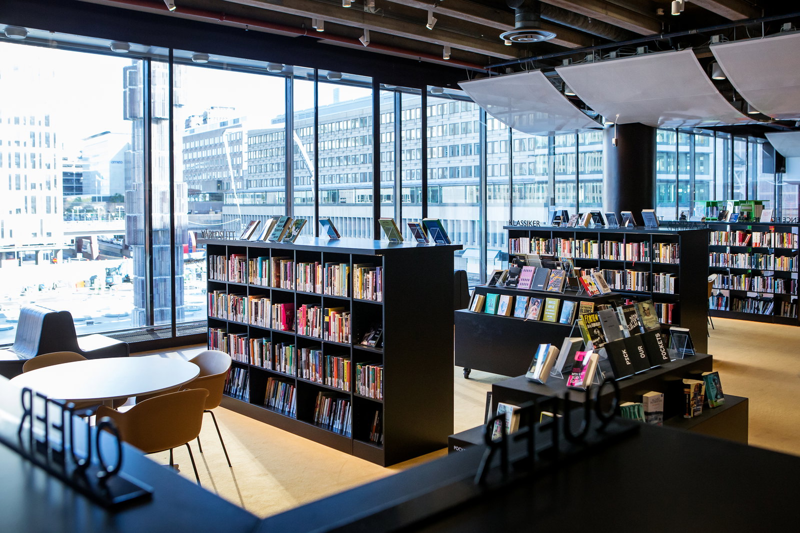 Bokhyllor i Kulturbiblioteket, med utsikt mot Glasobelisken vid Sergels torg.  