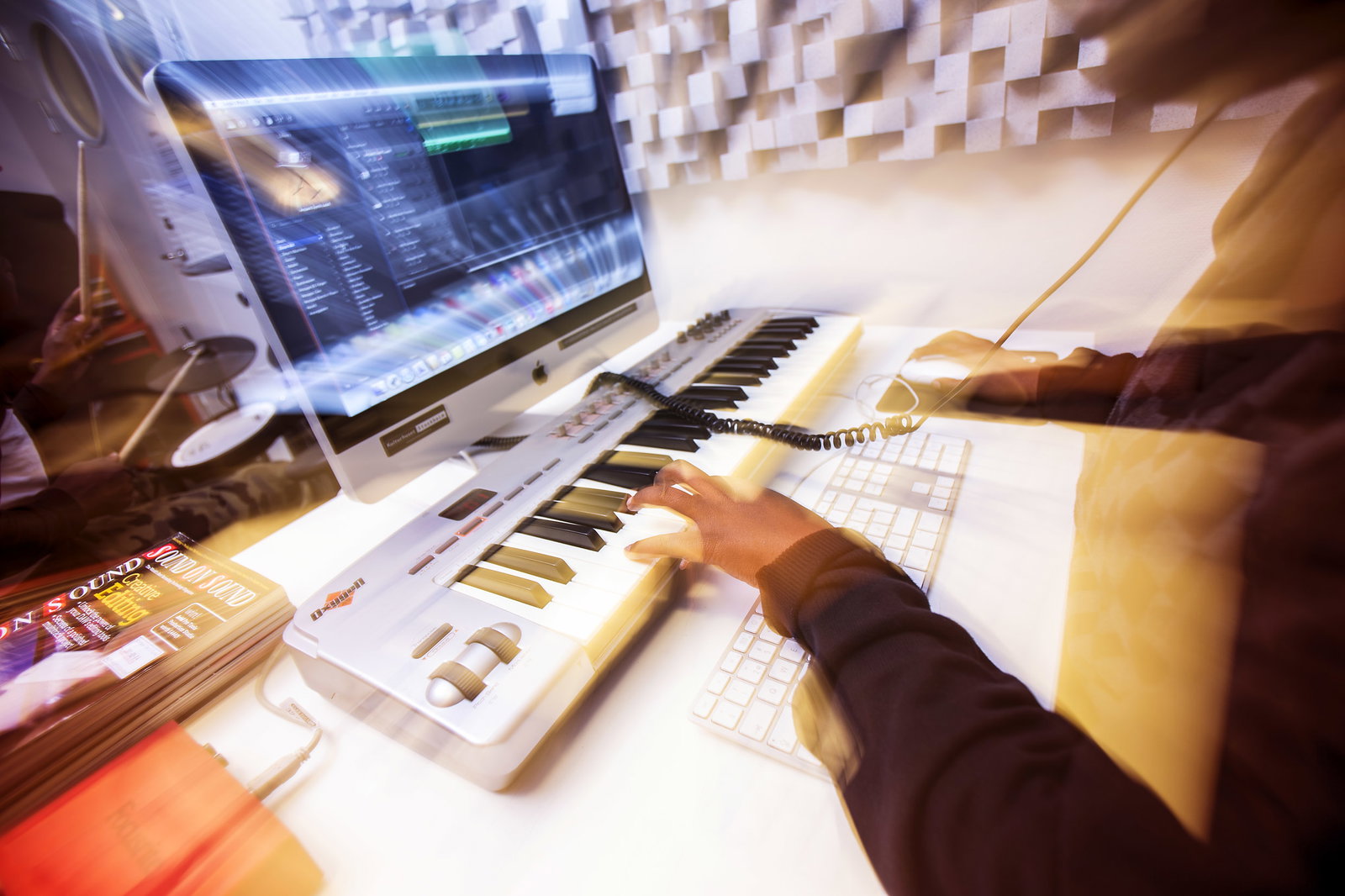 En person sitter vid en dator och jobbar med ett ljudredigeringsprogram.