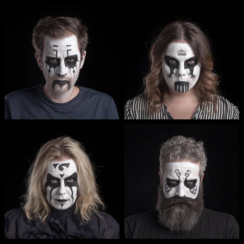 Fyra vuxna, två män och två kvinnor, 30–50 år, med svartvit ansiktsmålning i mörka tröjor/blus; en med långt skägg, mot svart bakgrund.