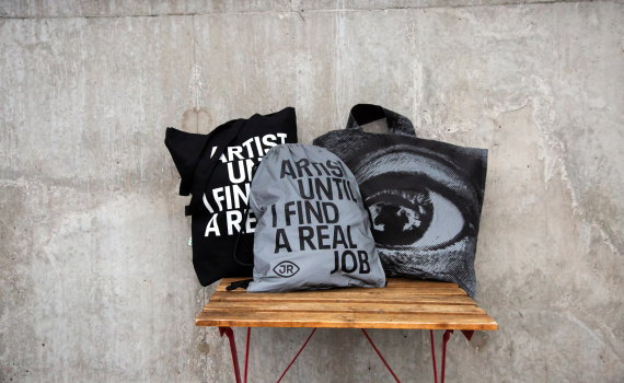 "Samling av JR-inspirerade väskor med budskapet 'Artist Until I Find A Real Job'. Snygga och praktiska för konstälskare på språng."