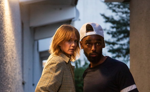 Två personer möts i en gränd och tar varandra i handen