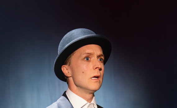 Halvdan i kostym och hatt tittandes förvånat