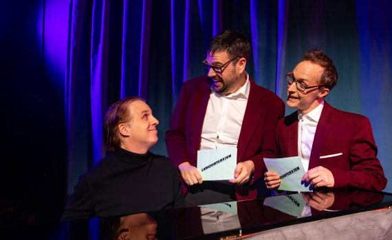 Helan och Halvdan i röda kavajer som intervjuar Fredrik vid pianot