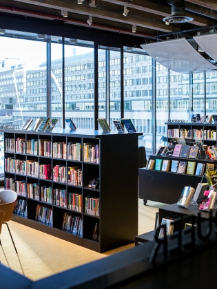 Bokhyllor i Kulturbiblioteket, med utsikt mot Glasobelisken vid Sergels torg.  