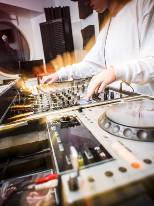 En person står vid ett DJ-set och spelar musik. 