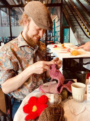 En man sitter och stickar på ett café i Kulturhuset. 