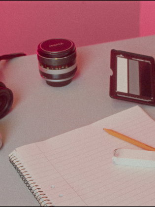 På ett bord ligger kameror, papper och pennor med mera. 