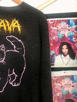 En tröja med ett tryck på i form av en lila katt och texten Lava. 