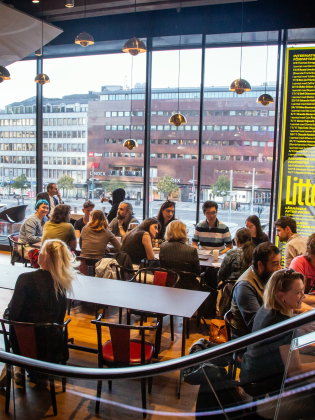 En grupp människor med olika bakgrunder samtalar runt ett bord på ett språkcafé.