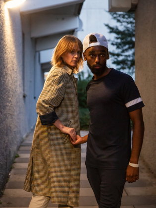 Två personer möts i en gränd och tar varandra i handen