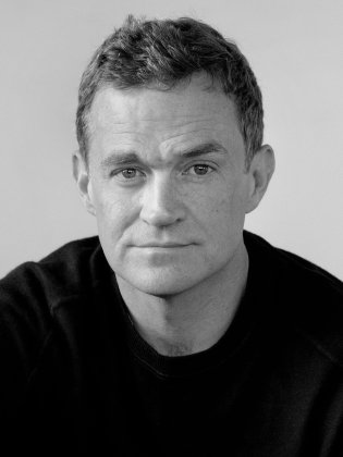 Patrick Radden Keefe porträtteras i svartvitt med direkt blick och neutralt uttryck, i en klassisk och avskalad komposition.