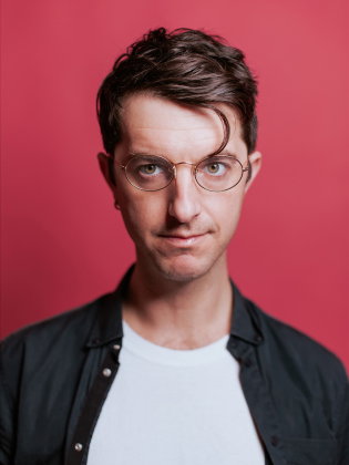 Vincenzo Latronico står framför en starkt rosa bakgrund i ett grafiskt och modernt porträtt där färgkontrasten förstärker den direkta blicken.
