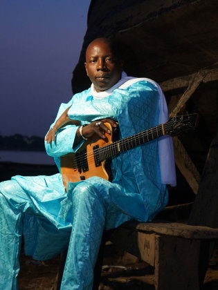 En man i turkosa kläder med en gitarr